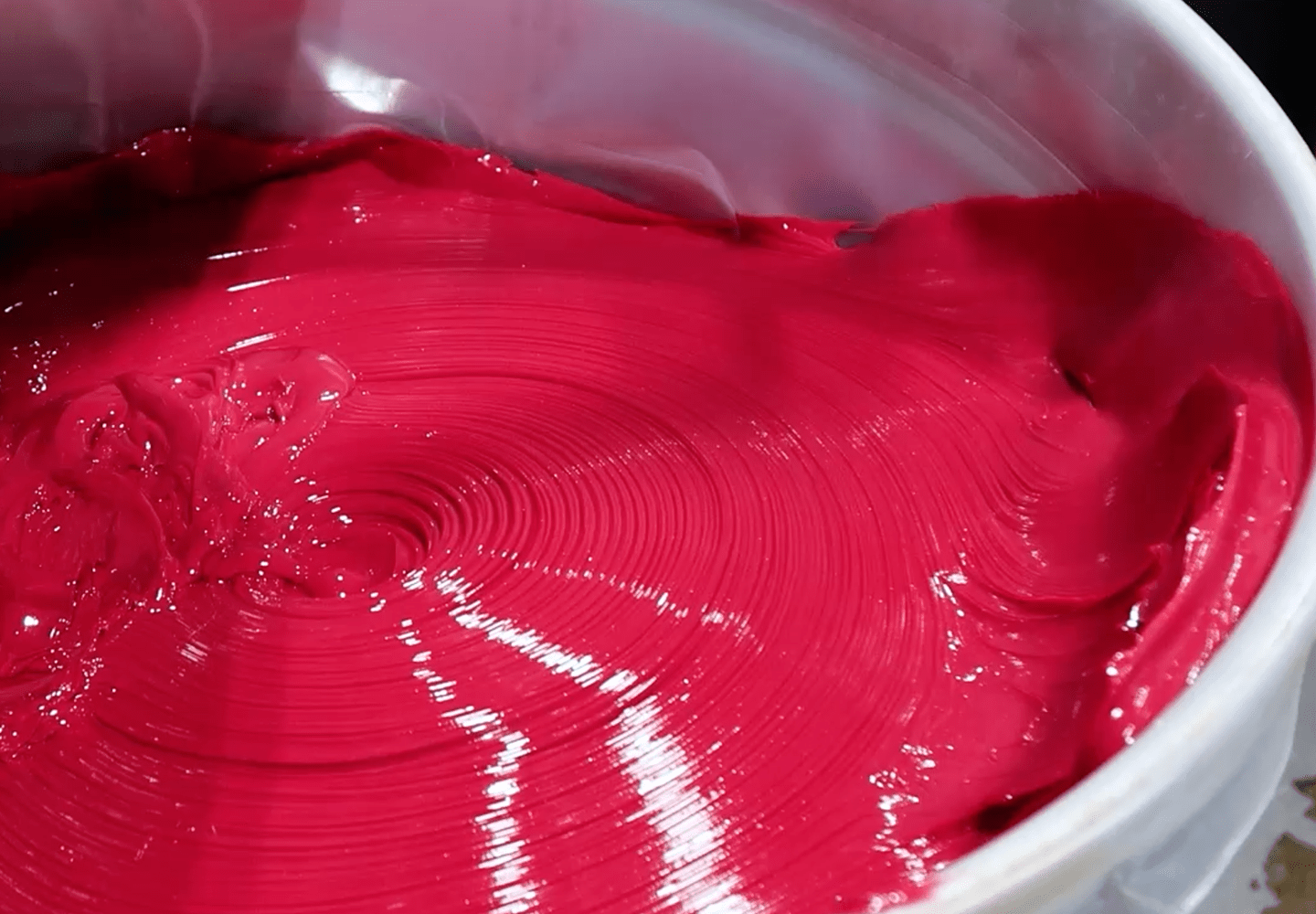 A tub of vibrant red lubricant with a smooth, glossy texture.