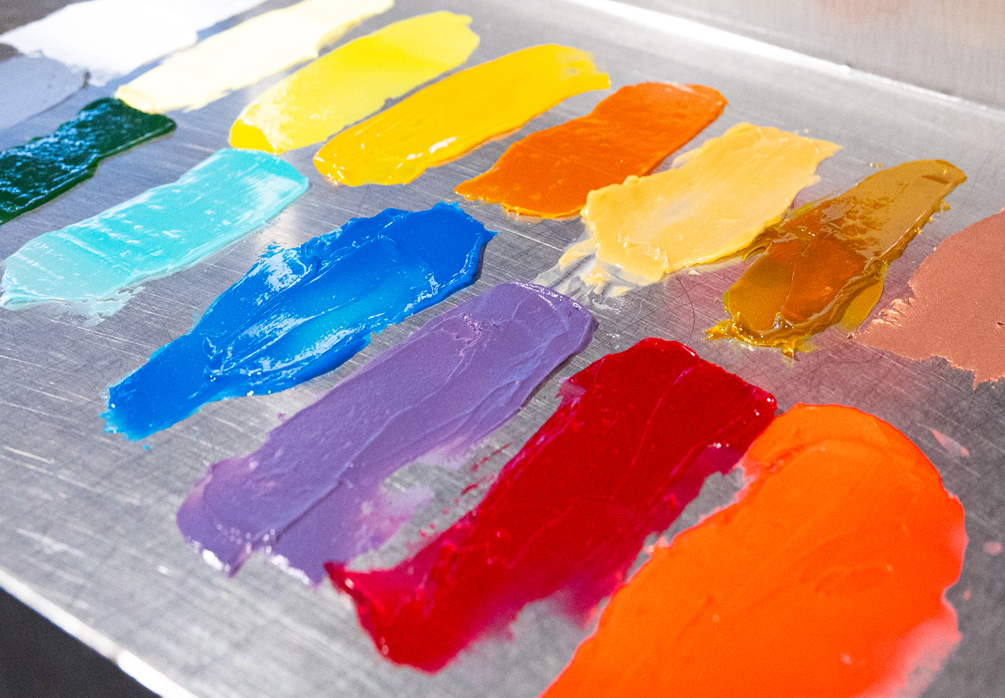 Colorful swatches of paint on a metallic surface, showcasing vibrant hues.