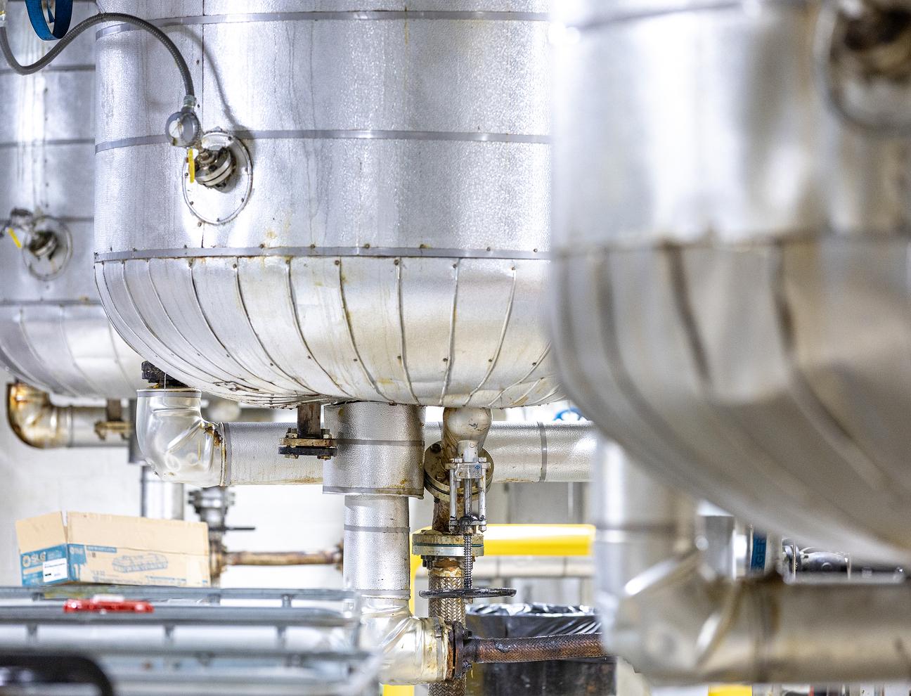 Industrial silver tanks with pipes in a production facility.
